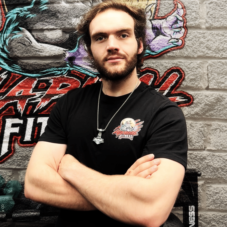 Image depicting a healthy young man with beard, arms folded in fron of a brick wall and logo for Capital Fitness