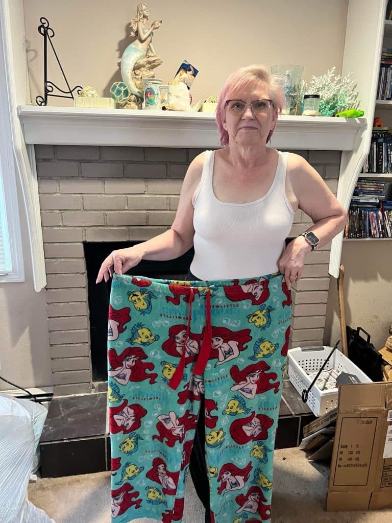 Angela after 10 months of training at Capital Fitness, holding up her old pants
